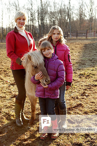 Porträt von Mutter und Töchtern  stehend mit Pony