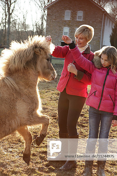 Mutter und Tochter im Freien  Anweisungen an Pony geben