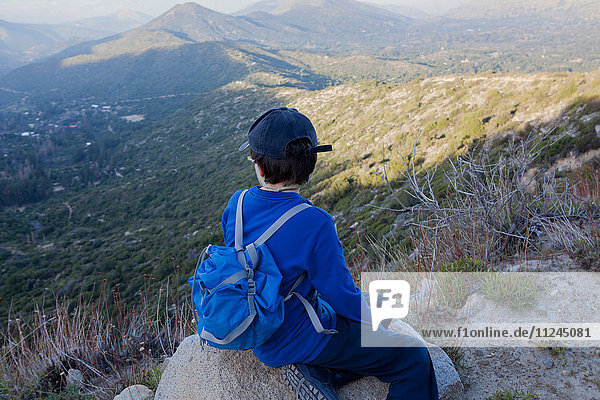 Junge sitzt auf einem Felsblock und schaut über die Anden  Valparaiso  Chile