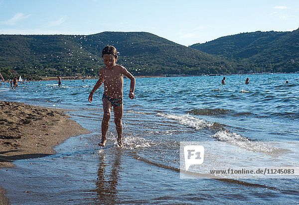Junge paddelt in den Wellen an der Küste  Italien