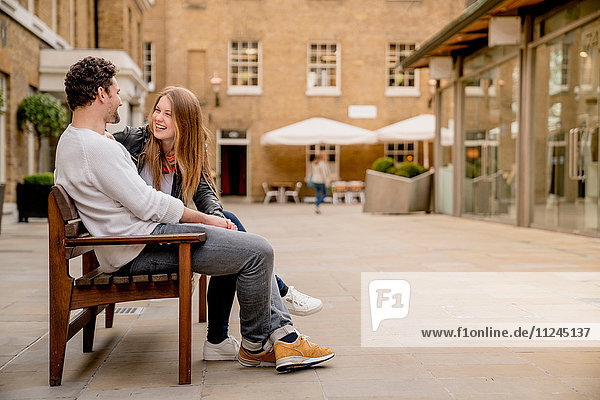 Junges Paar sitzt auf der Bank und plaudert  Kings Road  London  UK
