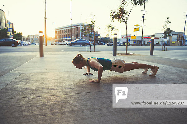 Young woman doing push-ups in street