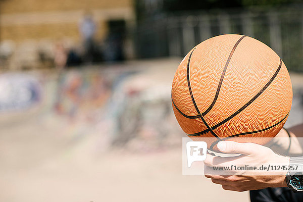 Junge Männer halten Basketball im städtischen Skatepark