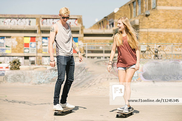 Junge Skateboardfreundinnen und -freunde skateboarden im Skatepark