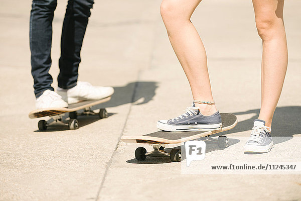 Beine von Skateboardfahrerinnen und Skateboardfahrern  die im Skatepark stehen