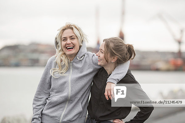 Portrait of two female runner friends laughing on dockside