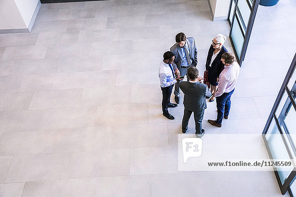 High angle view of businesswoman and men having discussion in office atrium