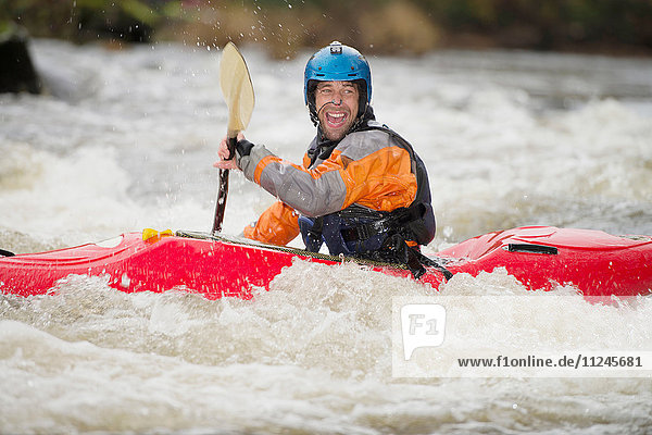 Happy male kayaker paddling River Dee rapids