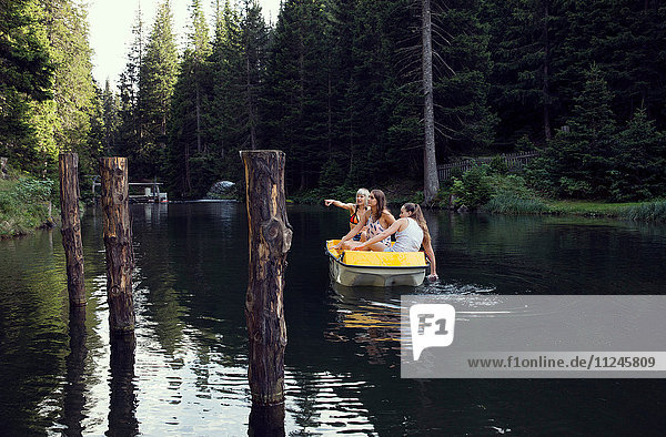 Drei erwachsene Freundinnen zeigen vom Ruderboot auf den See  Sattelbergalm  Tirol  Österreich