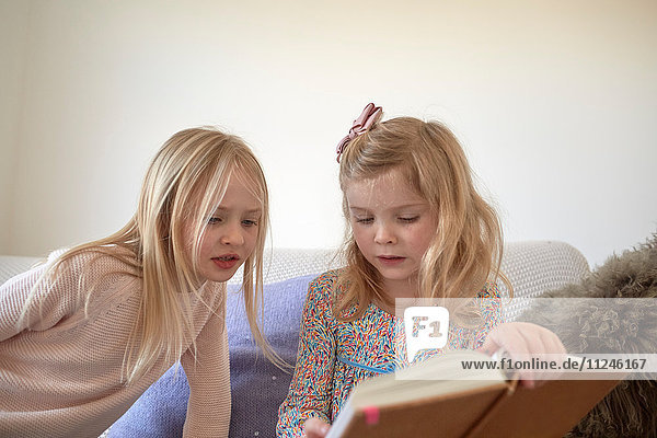 Mädchen und ihre Schwester lesen im Wohnzimmer