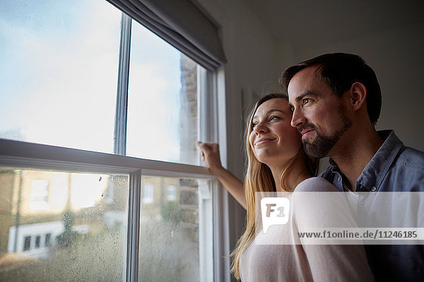Mid adult couple looking out through bedroom window