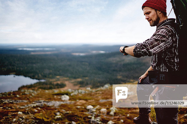 Wanderer bei der Zeitkontrolle auf dem Klippengipfel  Keimiotunturi  Lappland  Finnland