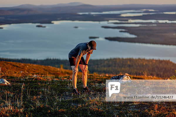 Mann ruht sich aus  nachdem er bei Sonnenuntergang auf den Klippen gelaufen ist  Keimiotunturi  Lappland  Finnland