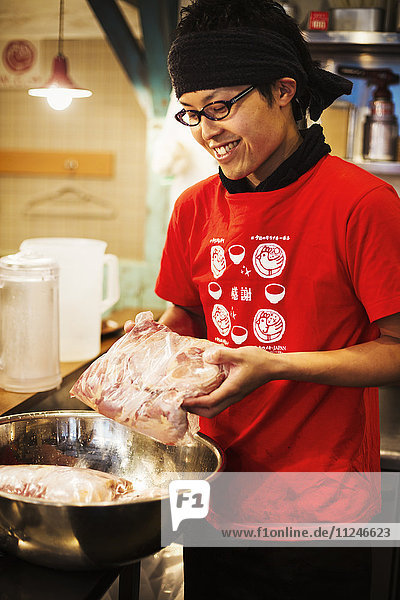 Der Ramen-Nudel-Laden. Ein Koch bereitet eine riesige Metallschüssel Brühe mit Fleischzutaten zu.