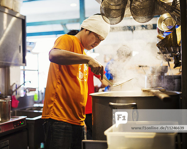 Der Ramen-Nudel-Laden. Das Personal bereitet das Essen in einer dampfgefüllten Küche zu.
