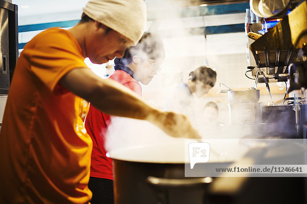 The ramen noodle shop. A chef stirring a huge pot of noodles cooking.