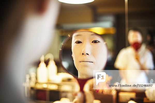 Eine moderne Geisha oder Maiko-Frau  die auf traditionelle Weise vorbereitet wird  mit weißem Gesichts-Make-up.