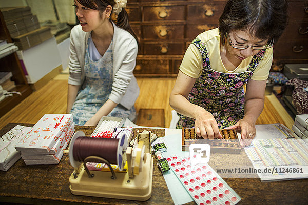 Ein kleiner handwerklicher Hersteller von speziellen Leckereien  Süßigkeiten namens Wagashi. Zwei Frauen arbeiten beim Packen von Bonbonschachteln für die Lieferung.