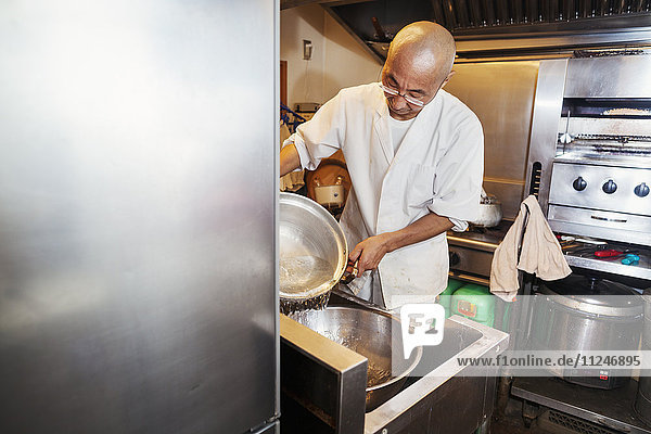 Ein Küchenchef  der in einer kleinen Großküche arbeitet  ein Itamae oder Meisterkoch  der Sushi zubereitet. Er bereitet Reis für die Gerichte vor.
