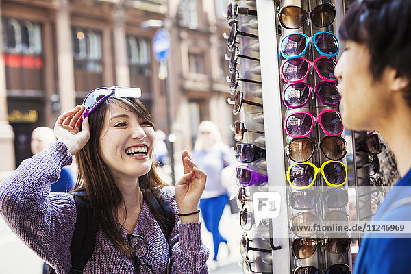 A Japanese woman trying on sunglasses in London  a summer tourist visitor.
