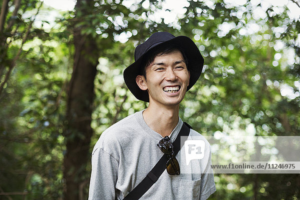 Smiling man wearing a hat standing in a forest.
