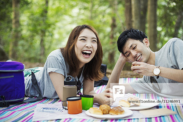 Young woman and man having a picnic in a forest.