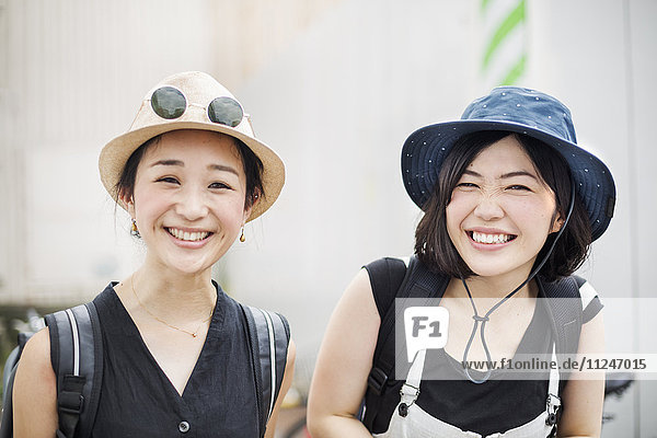 Porträt von zwei lächelnden jungen Frauen mit Hüten.
