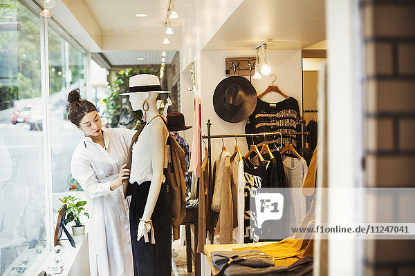 Frau  die in einer Modeboutique in Tokio  Japan  arbeitet und eine Schaufensterpuppe ankleidet.