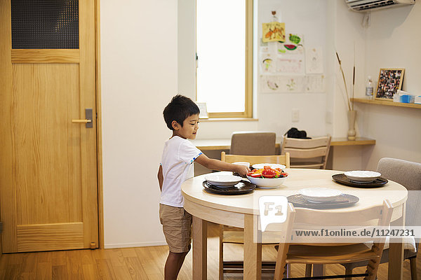 Family home. A boy setting the table for a meal.