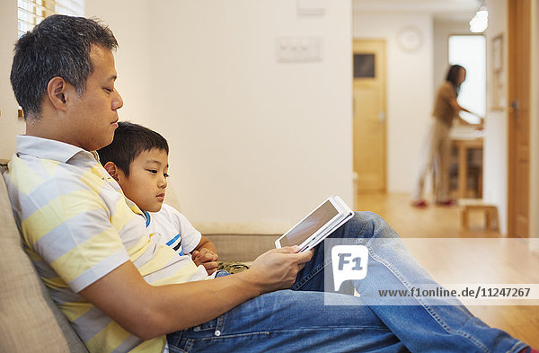 Familienhaus. Ein Mann und sein Sohn sitzen und lesen ein Buch.
