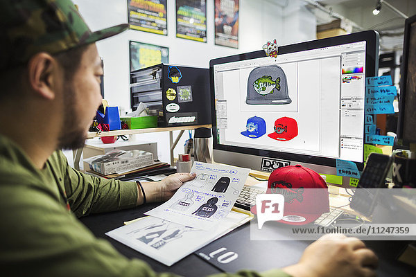 Ein Mann  ein Designer  der am Bildschirm arbeitet und Entwürfe für Baseballcaps entwirft.