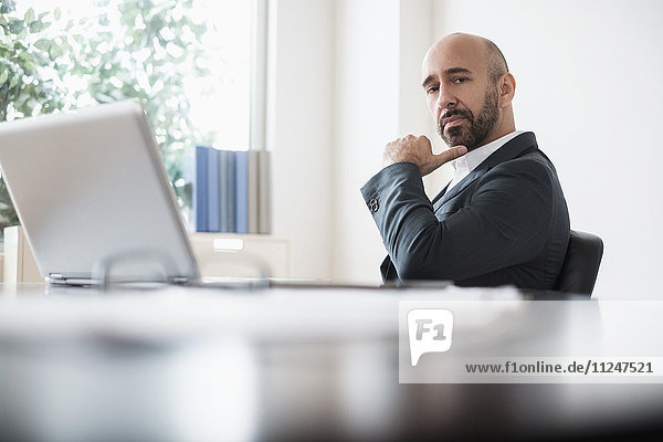 Serious businessman sitting at desk in office