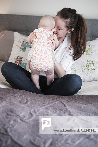 Mutter spielt mit ihrer kleinen Tochter (2-5 Monate) im Schlafzimmer