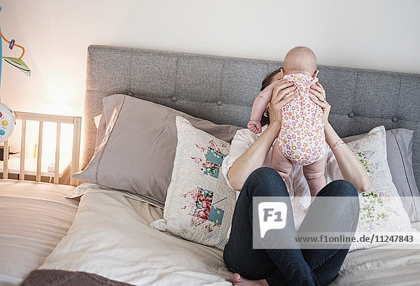 Mother playing with baby daughter (2-5 months) in bedroom