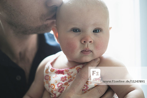 Vater küsst den Kopf seiner Tochter (2-5 Monate)