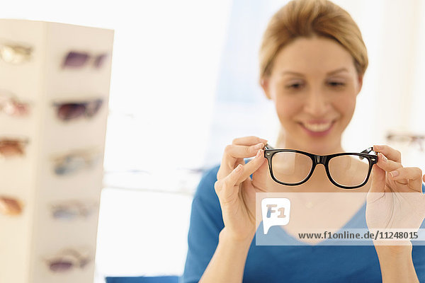 Woman and choosing eyeglasses in store