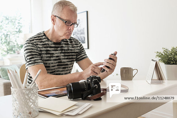 Man in home office using smartphone