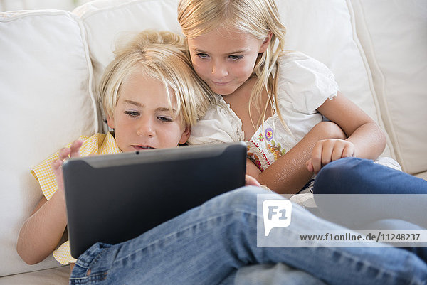 Mädchen (6-7) und Junge (4-5) schauen auf ein digitales Tablet