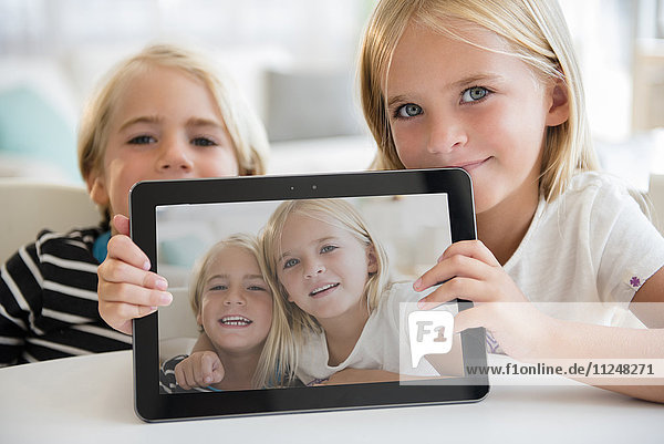 Sister (6-7) and brother (5-6) showing picture on digital tablet