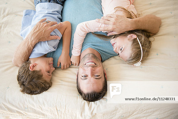 Father lying down with son (8-9) and daughter (6-7)