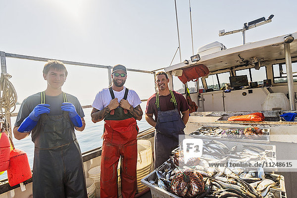 Portrait of three fishermen standing on boat