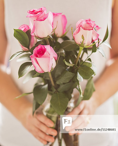 Mid section of woman holding bunch of pink roses