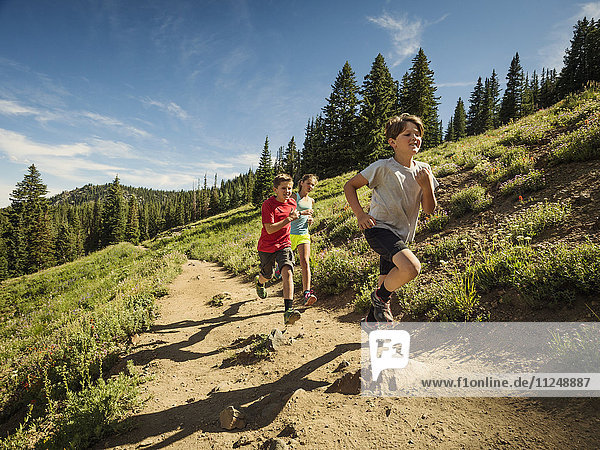 Three children (10-11  12-13  14-15) running in mountains