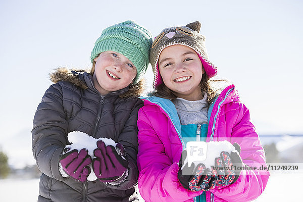 Portrait of girls (8-9 10-11) holding snow