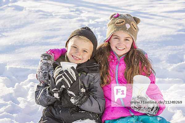 Boy (8-9) and girl (10-11) warming up drinking hot chocolate