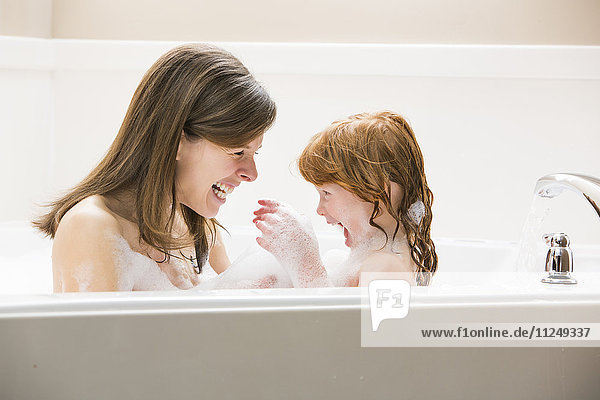 Mother and daughter (4-5) having bubble bath