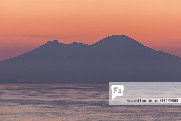 Silhouette der Berge mit Meer im Vordergrund bei Sonnenuntergang