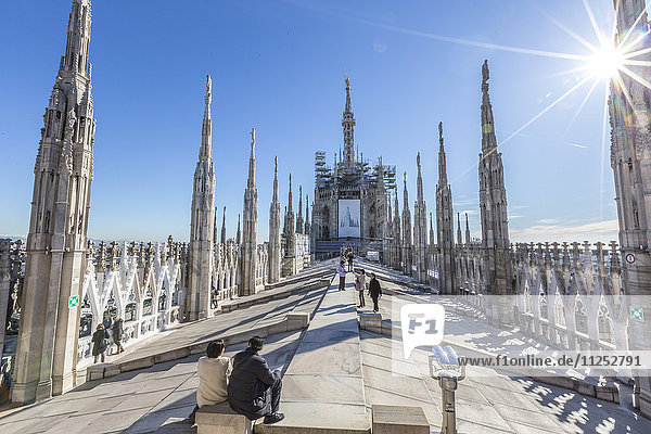 Tourists among the white marble spiers on the top of the Duomo  Milan  Lombardy  Italy  Europe