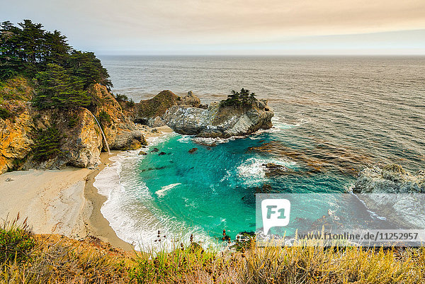 Smoky skies from a nearby wildfire turn the land orange at McWay Falls  California  United States of America  North America