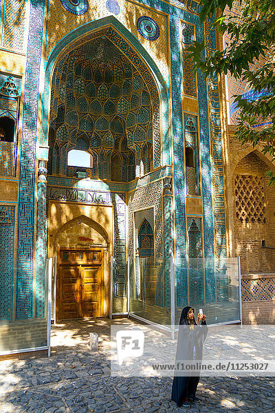 Junges iranisches Mädchen im Tschador beim Fotografieren vor der Jameh-Moschee  Natanz  Iran  Naher Osten